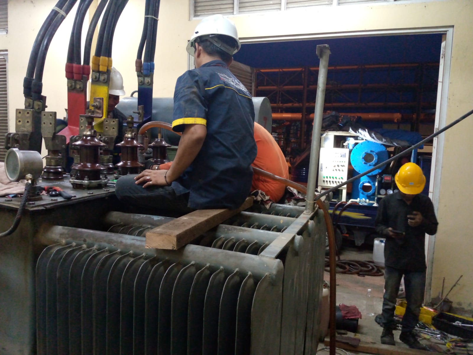 Proses purifikasi minyak trafo on-site dengan mesin filter vakum — teknisi PT TEM bekerja di atas transformator distribusi
